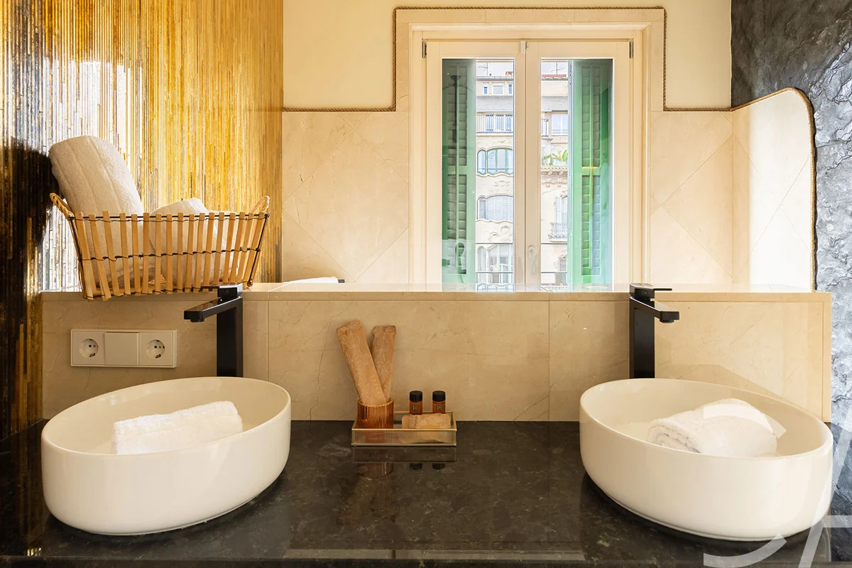 Salle de bains contemporaine de style spa, dotée d'une spacieuse douche à l'italienne à effet pluie, de finitions en marbre haut de gamme et d'un éclairage raffiné, dans un appartement de luxe avec services hôteliers à louer dans le quartier de l'Eixample à Barcelone